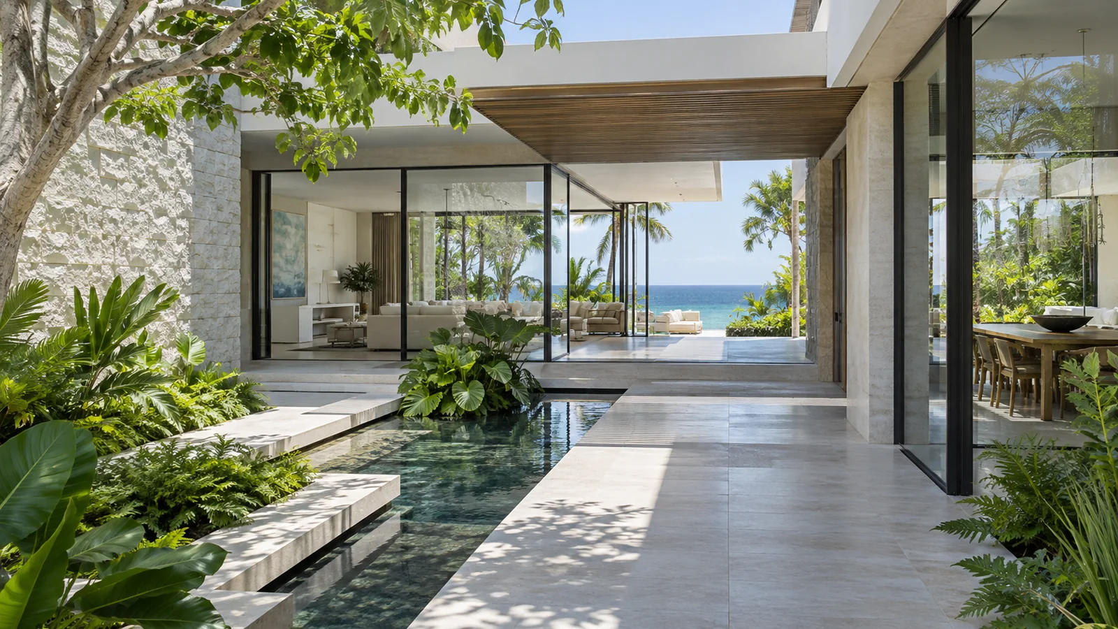 Layered tropical home breezeway connecting a pale courtyard, glass rooms, gardens, and ocean