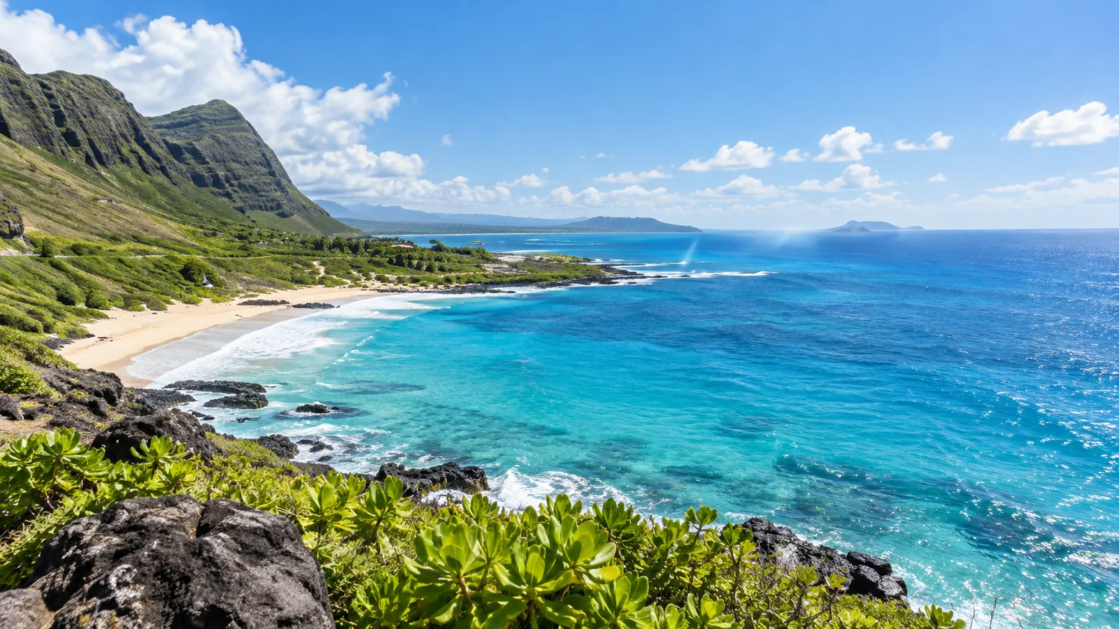 Bright Hawaiian coastline with turquoise water, pale sand, volcanic rock, and green coastal foliage